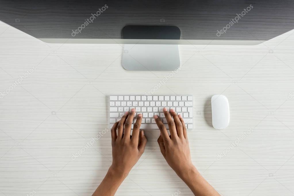 Hand liegt auf einer Computermaus neben einer Tastatur.